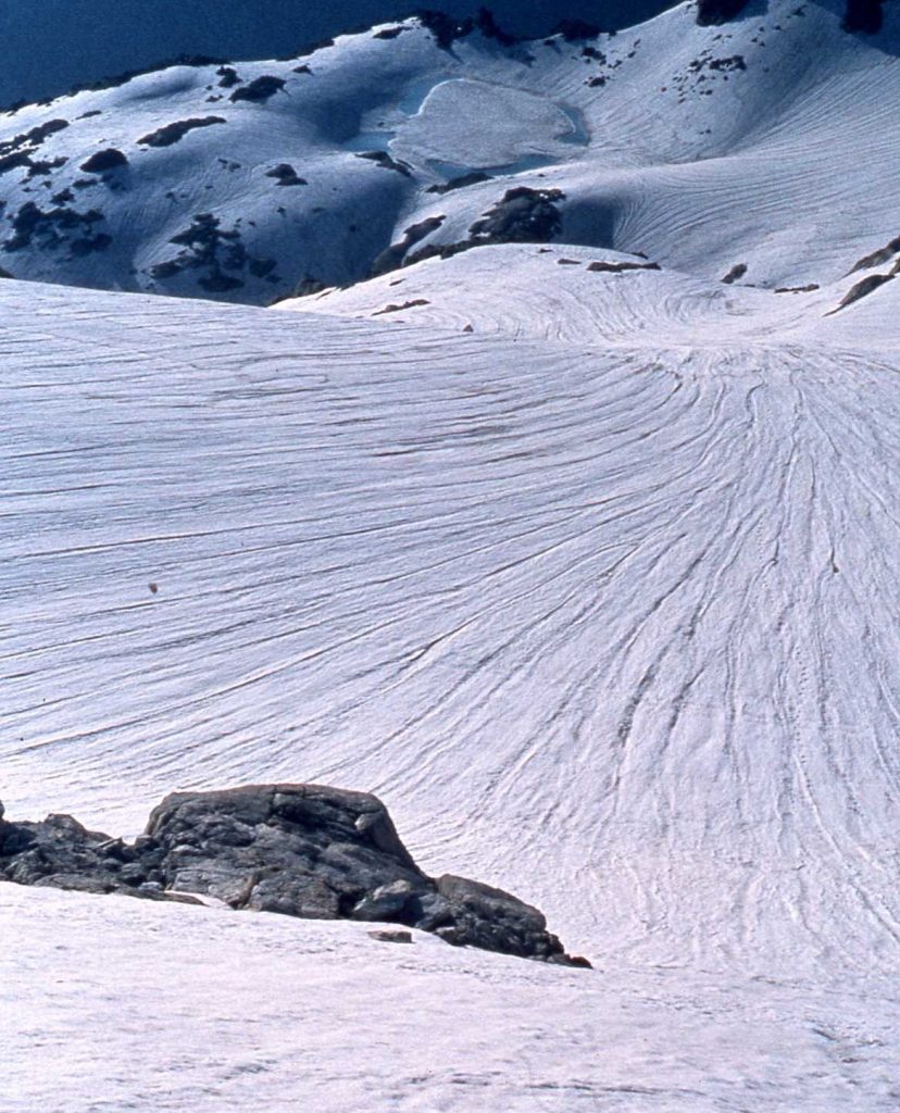 El Estany Gelat de Comaloforno en julio de 1983. Representaba en sus 2.685 metros de altitud, el límite inferior del antiguo helero del mismo nombre. A su derecha, en la vertiente norte del Pico de Comaloforno (3.033 m), resistió hasta finales de la década de los años 1970 uno de los últimos restos residuales de hielo glaciar en Cataluña. (Jordi Camins).